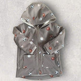 Beigegraue Kinder Softshelljacke mit  Fußbällen, Basketball- und Baseball-Motiven, Kapuze und hohem Kragen.