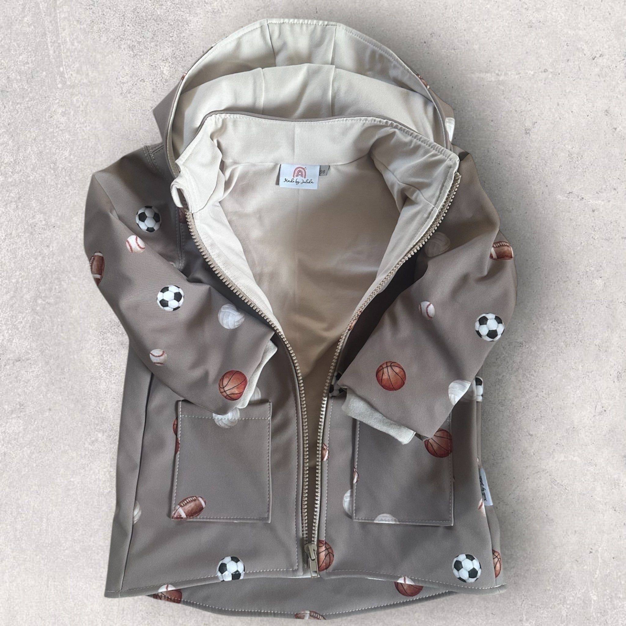 Detailansicht der Kinderjacke: Weiches Beiges Jersey-Innenfutter und Reißverschluss mit schützendem Kinnschutz.